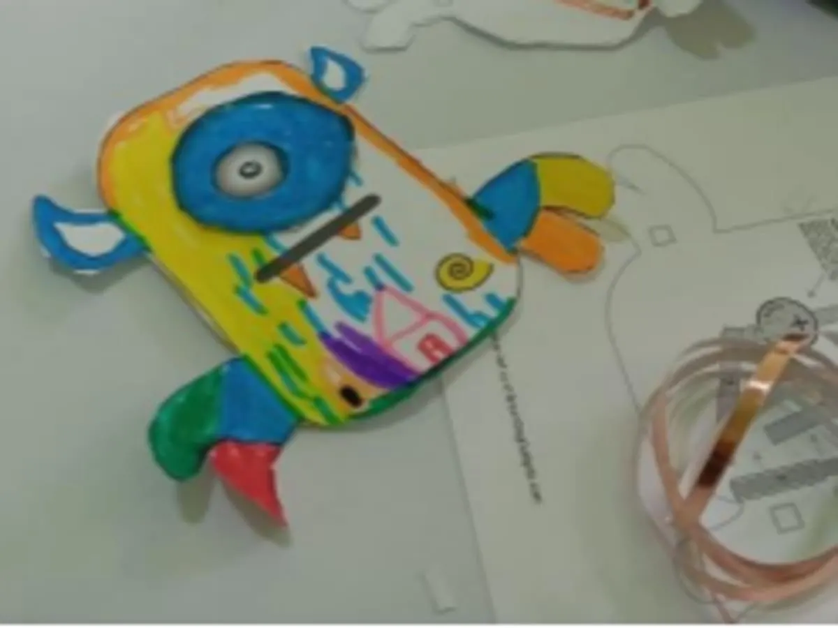 Illustration d’un petit monstre coloré fabriqué à la main avec du carton et des matériaux de bricolage. Avec son grand œil bleu et ses formes fantaisistes, il évoque une activité créative amusante où l’imagination est à l’honneur.