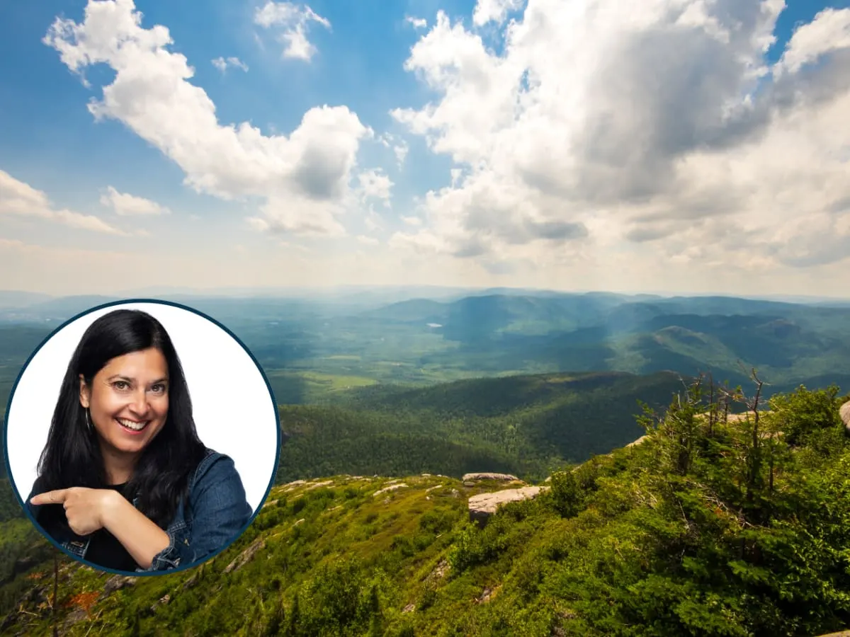 Cette image montre un vaste paysage montagneux vu depuis un point élevé et dans le coin inférieur gauche se trouve le portrait de Nathalie Gemme.