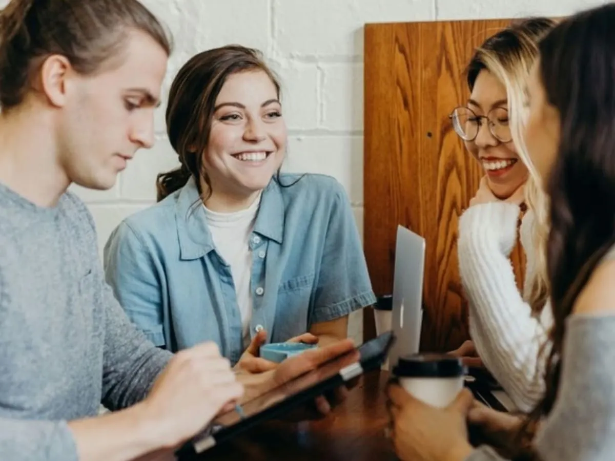 Quatre personnes assises autour d'une table discutent en souriant.