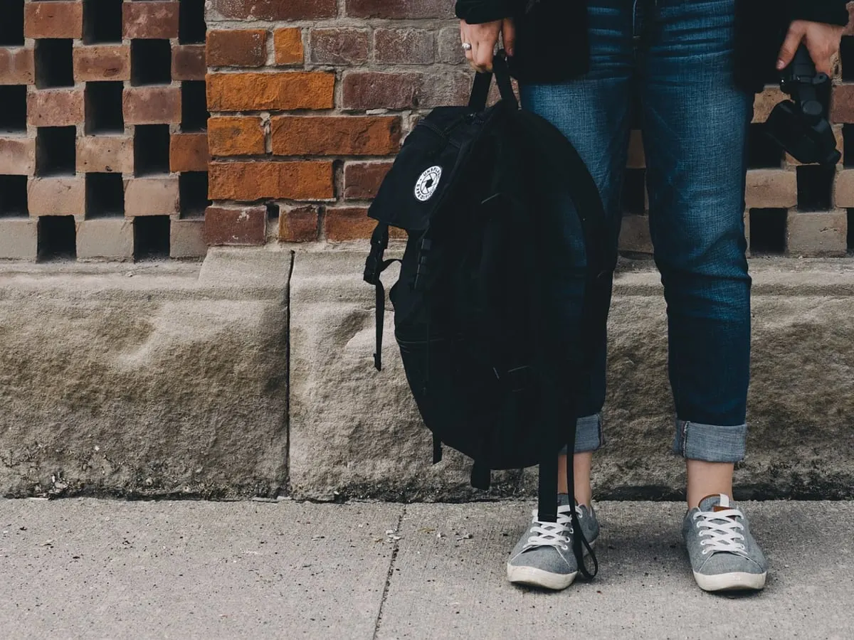 Sac à dos noir tenu par la main par une personne
