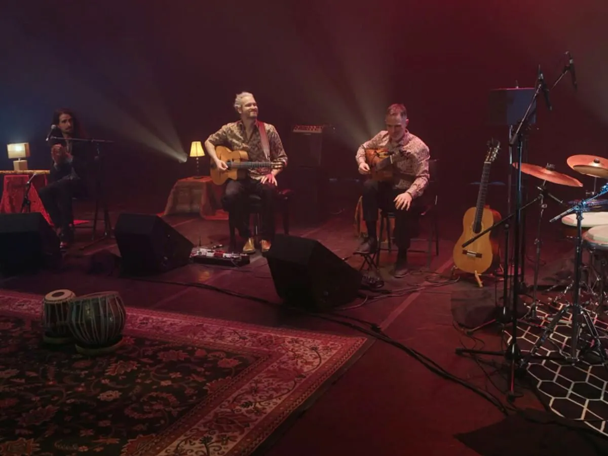 Cinq musiciens sur une scène décorée avec des tapis persans performent.