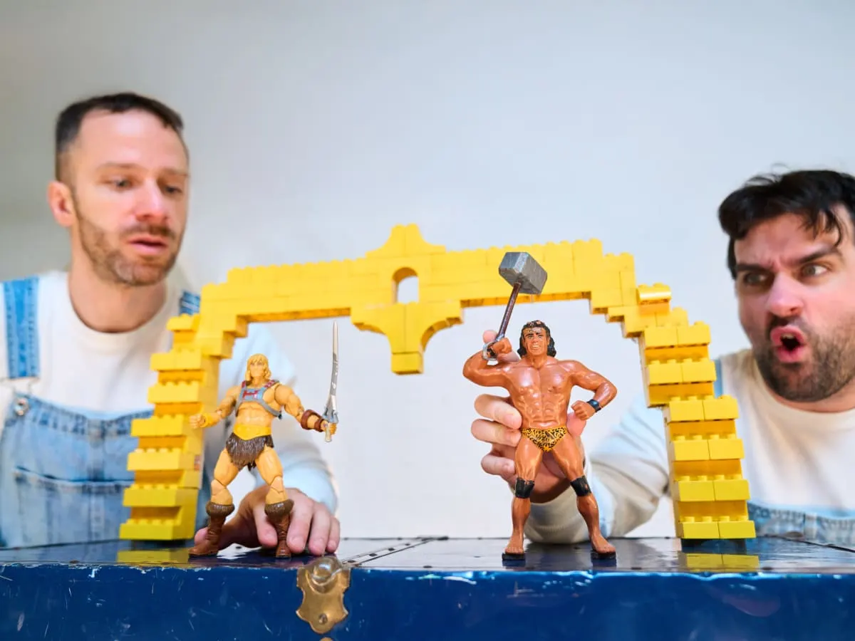 Deux hommes jouent avec des figurines sur une surface bleue.