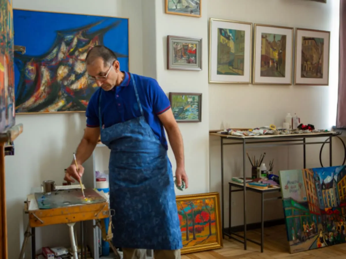 L'image montre Areg Elibekian qui se tient au centre un atelier de peinture.