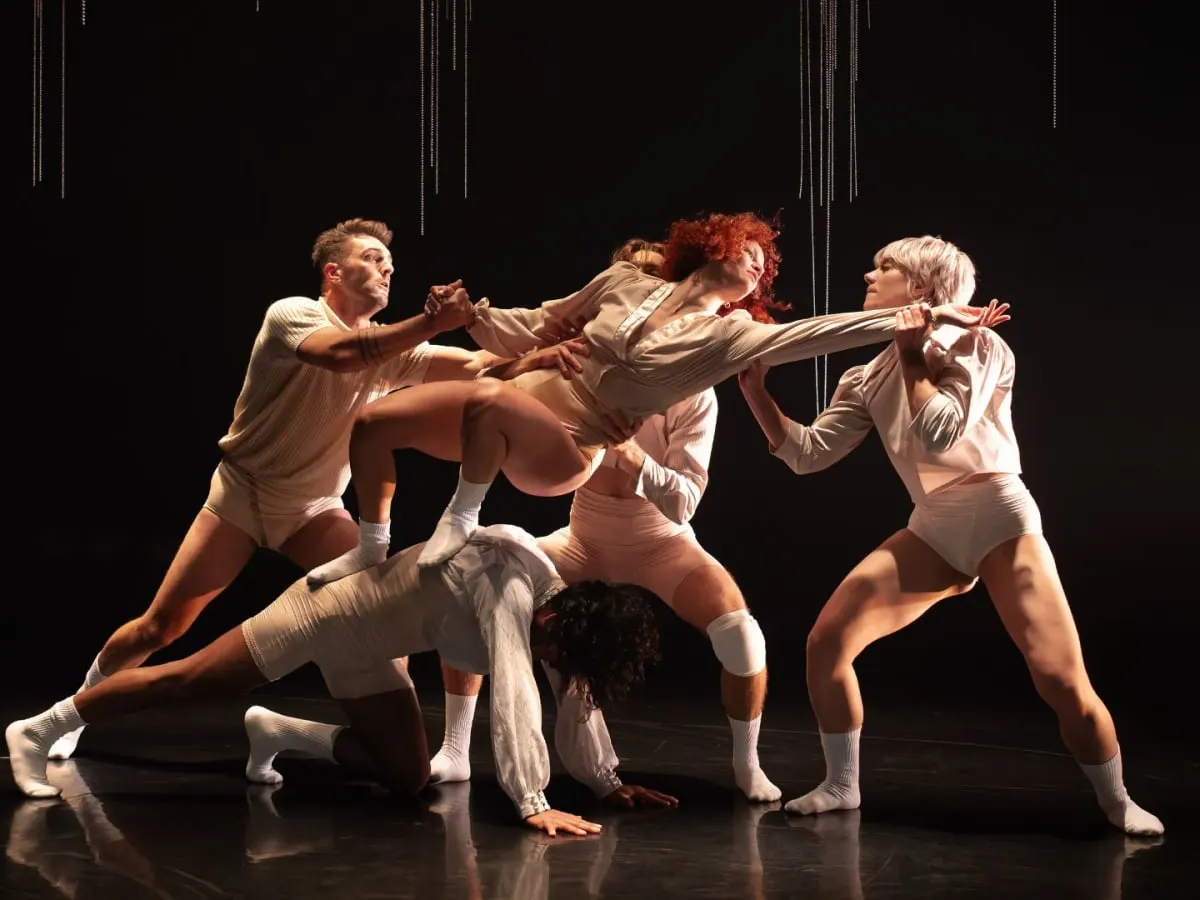 Un groupe de danseurs qui exécutent une figure collective dynamique de danse contemporaine.
