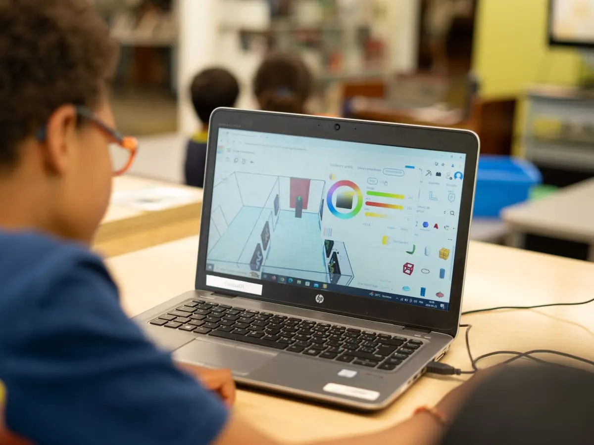 Un enfant travaille à l'ordinateur. On peut voir sur son écran un personnage en trois dimensions à travers le logiciel de modélisaton 3D Tnkercad.