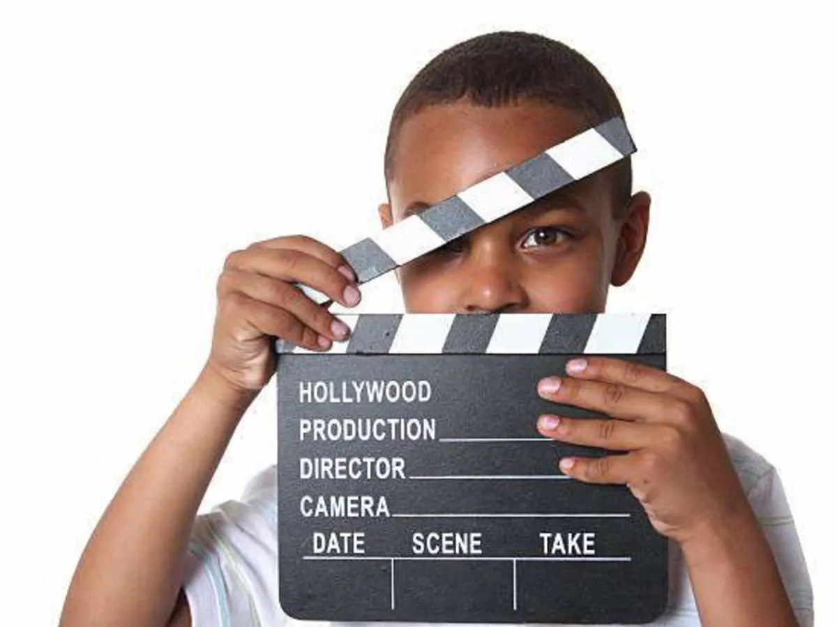 Une photo d'un jeune tenant un clap de cinéma