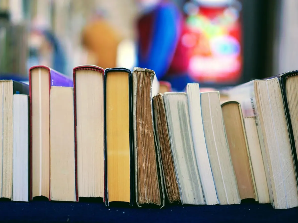 Photo de plusieurs livres couchés sur le côté sur un fond coloré
