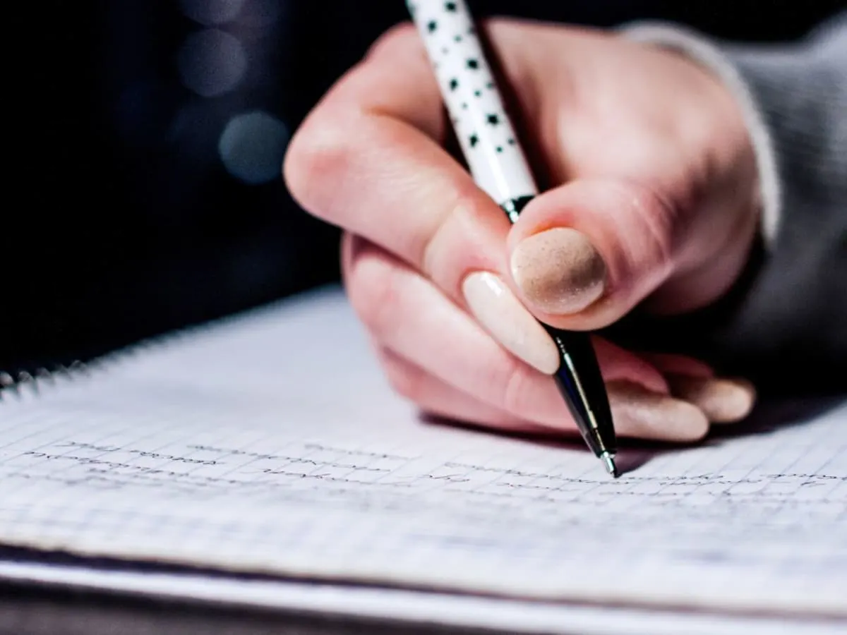 Une personne en train d'écrie au stylo-bille dans un cahier.