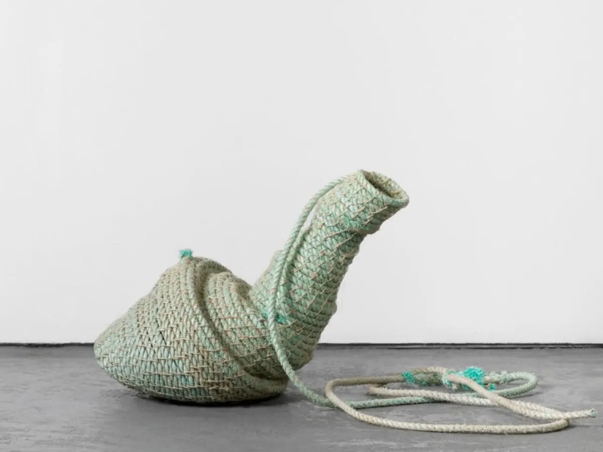 Fil de couleur gris-turquoise formant un escargot devant un mur blanc