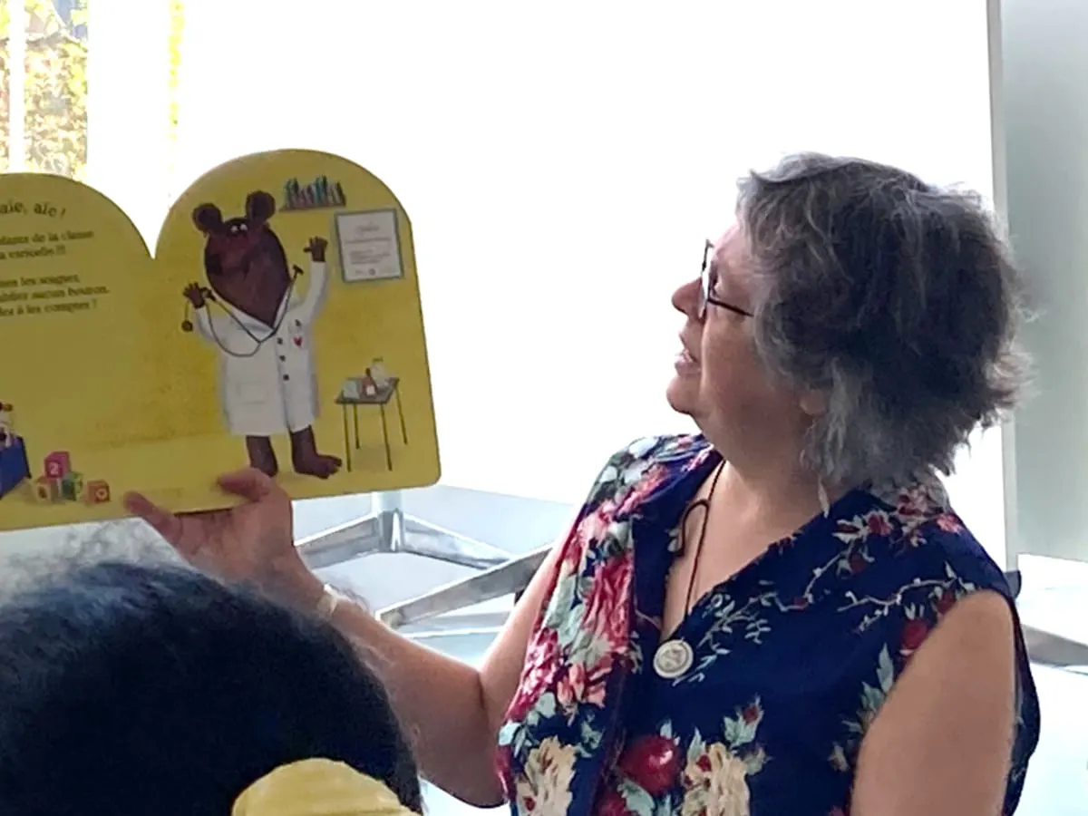 Photo d'une conteuse avec un livre ouvert devant les enfants
